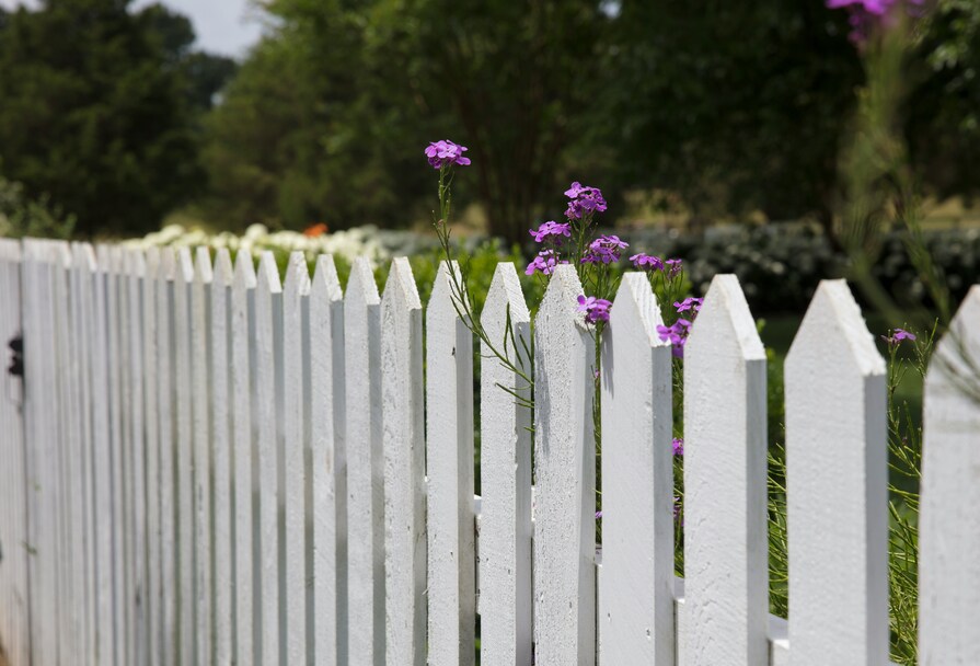 Weißer Lattenzaun vor Garten mit Blumen